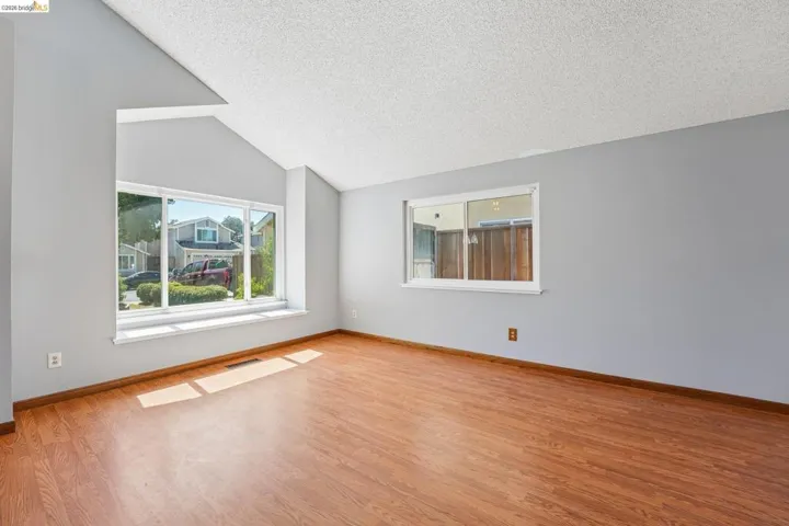 Open living area featuring a vaulted ceiling and wood-finish flooring