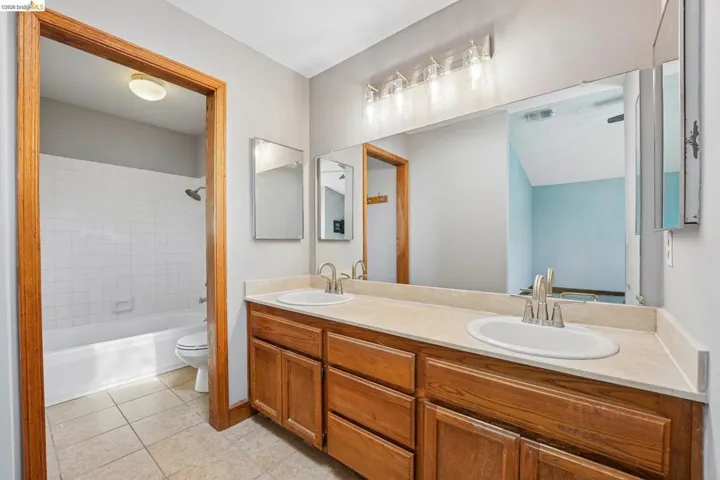 Bathroom featuring a double vanity with wood cabinetry, light-colored countertop, and dual oval sinks