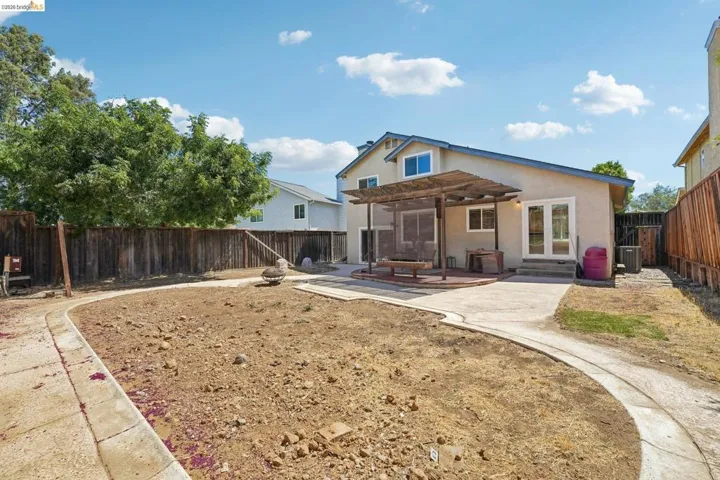 Rear exterior featuring a large concrete patio, an attached wood pergola, and double French doors