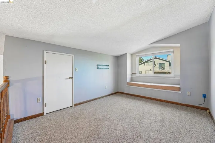 Carpeted room with sloped ceilings and light grey walls
