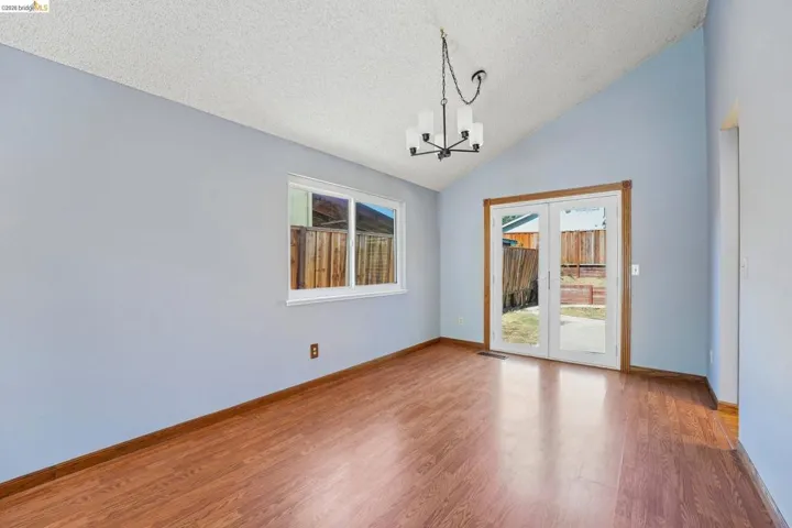 Vaulted ceiling interior with wood-finish flooring, featuring a contemporary chandelier and light blue walls