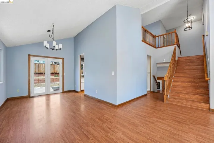Spacious interior featuring wood-finish flooring, vaulted ceilings, and a prominent staircase with wood railings