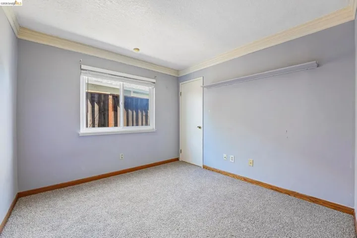 Carpeted interior space featuring light blue walls and white crown molding