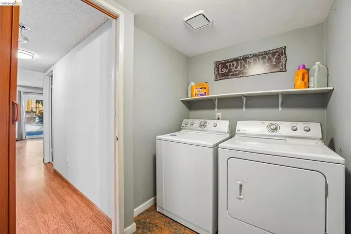 Dedicated laundry area featuring a white floating shelf, neutral wall tones, and tiled flooring