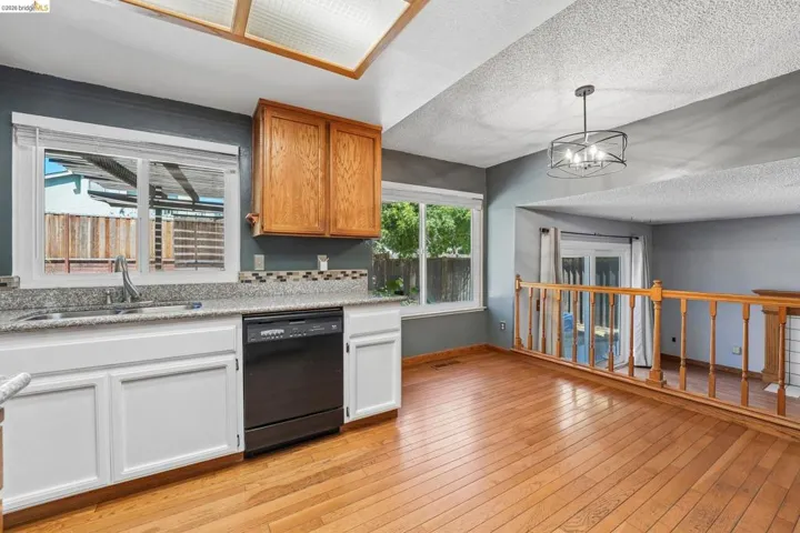 Kitchen featuring a stainless steel sink, black dishwasher, and white lower cabinetry