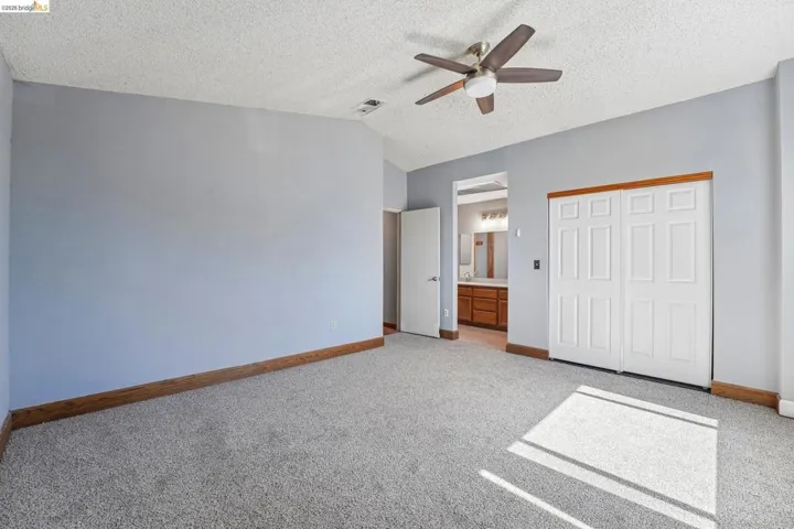 Spacious room featuring vaulted ceilings, light gray wall paint, and wood-finish baseboards