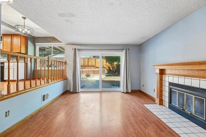 Inviting living space featuring wood-finish flooring, a traditional wood mantelpiece, and a tiled fireplace surround