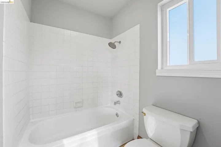 Bathroom featuring a white subway tile shower surround, showerhead, and tub with chrome fixtures