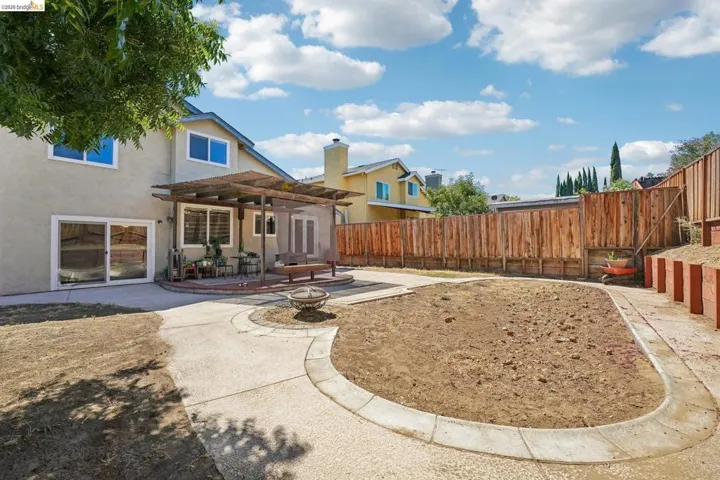 Expansive backyard featuring a large patio, a wood pergola, and a circular concrete pathway