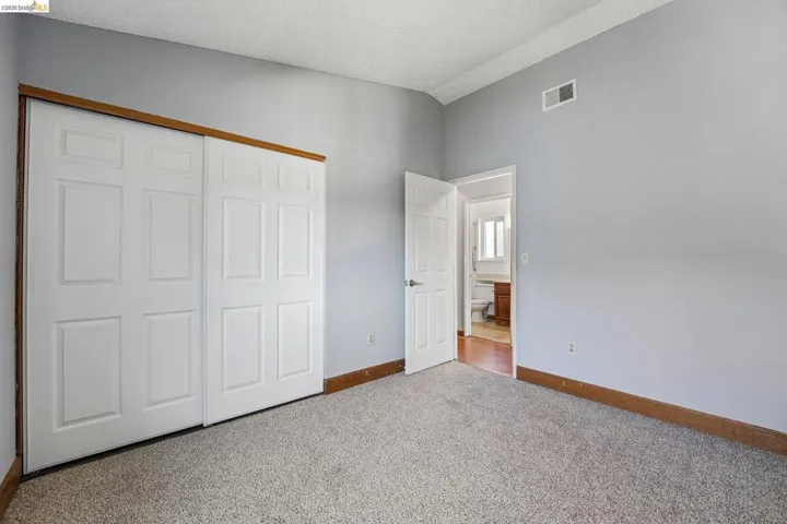 Carpeted room featuring light gray walls, a white paneled closet with wood trim, and a white paneled interior door