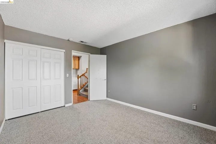 Carpeted room with neutral grey wall paint and white baseboards