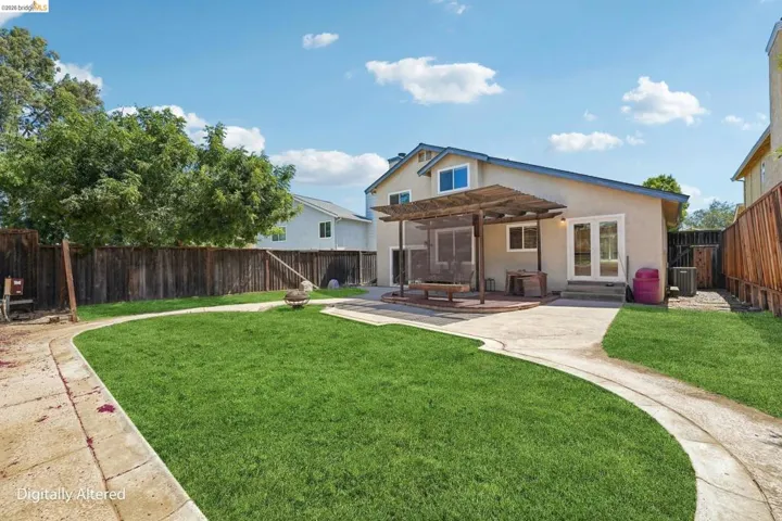 Expansive backyard featuring a lush lawn, curved concrete pathways, and a spacious patio with a wooden pergola