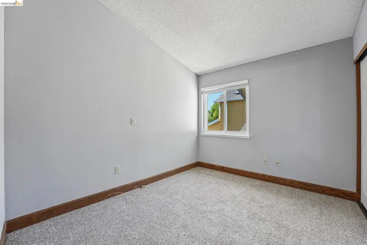 Neutral-toned room featuring light gray walls, textured white ceiling, and carpeting