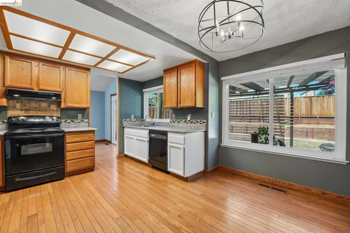 Kitchen featuring wood-finish flooring, oak cabinetry, and granite-style countertops