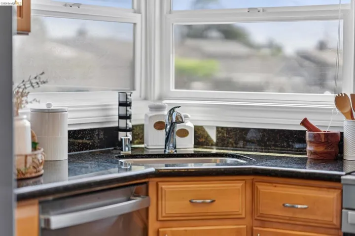 Corner kitchen sink with a chrome faucet, set against a dark granite countertop and matching backsplash