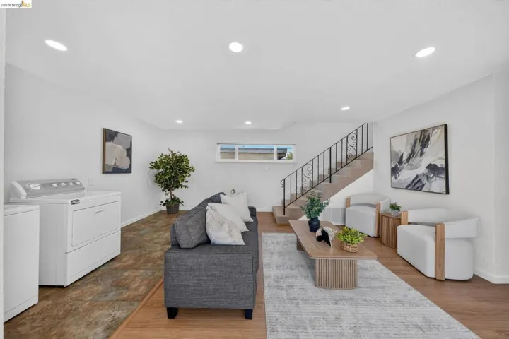 Open-concept living space featuring recessed lighting, a staircase with wrought iron railing, and a window providing natural light