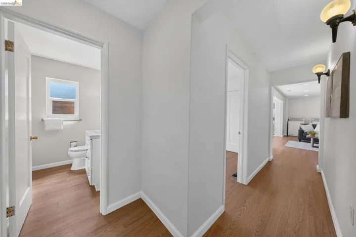 Corridor featuring wood-finish flooring, white baseboards, and neutral wall paint