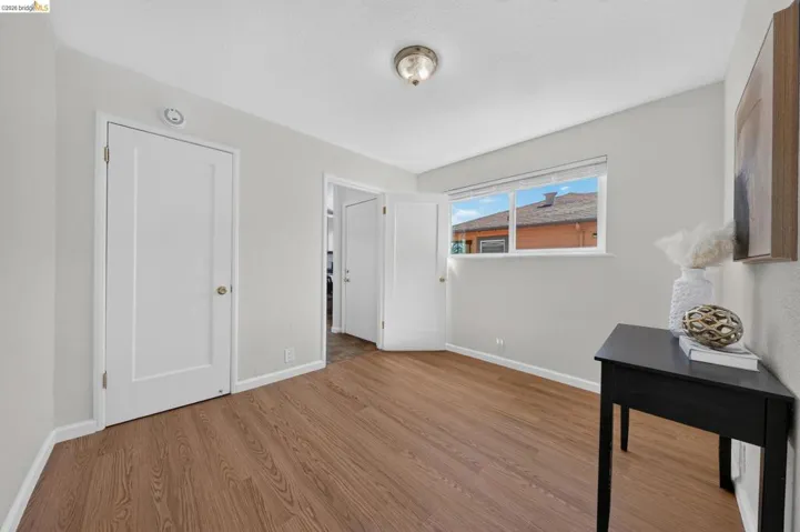 Interior room featuring wood-finish flooring, light neutral wall paint, white trim, and a ceiling-mounted light fixture