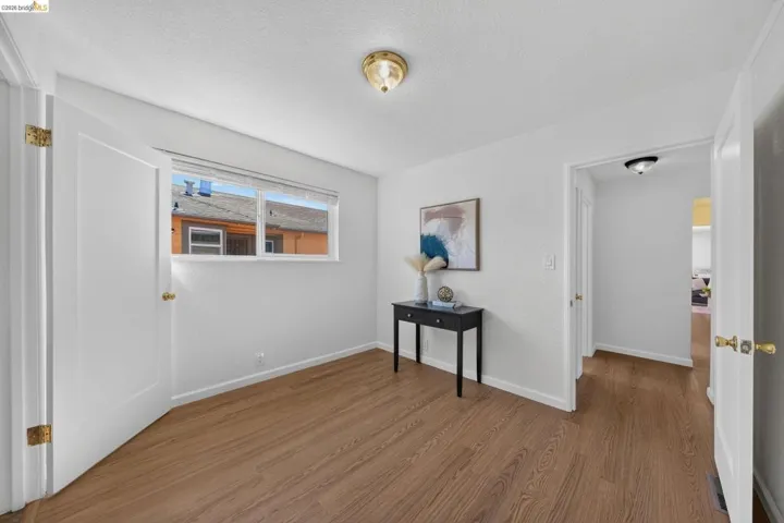 Bright room featuring wood-finish flooring, white walls, and a window for natural light
