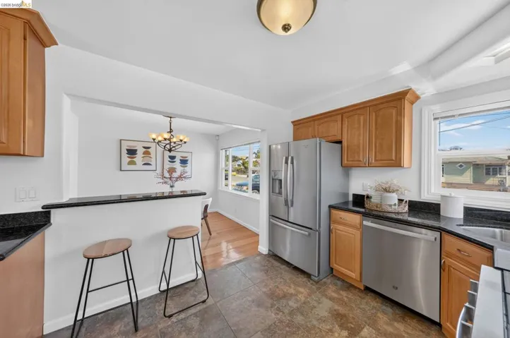 Kitchen featuring wood cabinetry, black countertops, stainless steel appliances, and a breakfast bar