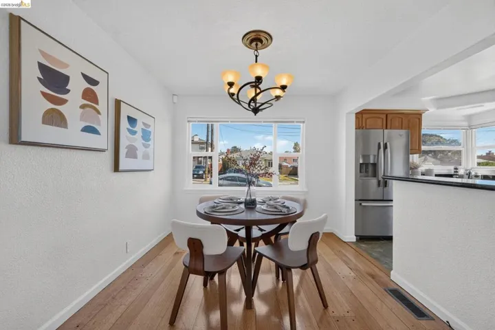 Open dining area featuring wood-finish flooring, a contemporary chandelier, and a large window