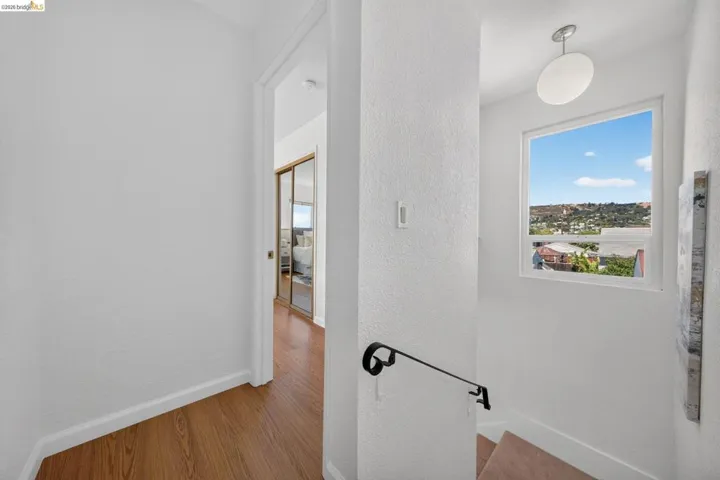 Stairwell featuring a contemporary light fixture, a large window, a black metal handrail, and carpeted steps