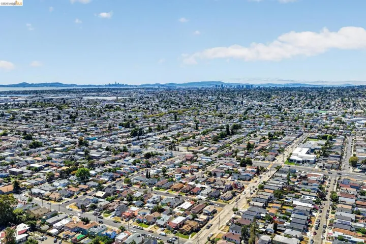 Expansive aerial view of a residential neighborhood with a distant cityscape and bay