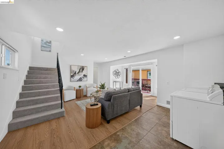 Open concept living area featuring wood-finish flooring, recessed lighting, and a staircase with carpeted treads and a metal railing