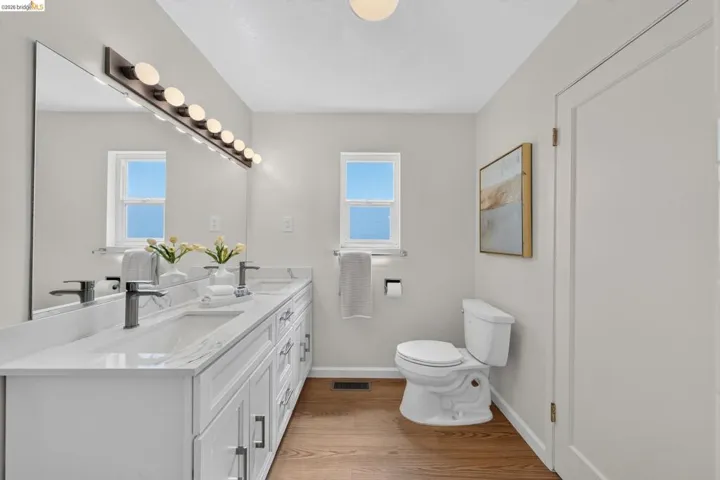 Double vanity with white cabinetry, matte black hardware, and an expansive mirror
