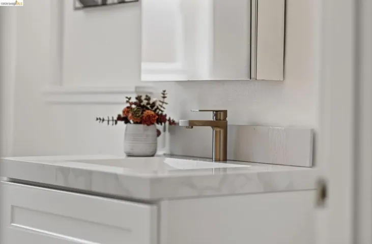 Modern vanity featuring a built-in sink, stone-finish countertop, and a contemporary bronze-finish faucet