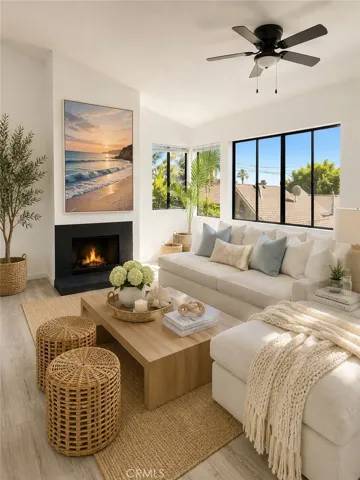 Spacious living room featuring vaulted ceilings, abundant natural light, a cozy fireplace, and large picture windows