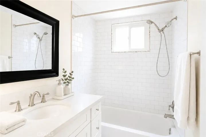 Beautifully updated bathroom featuring a timeless subway tile tub/shower surround, modern vanity, contemporary fixtures, and a large window that fills the space with natural light.