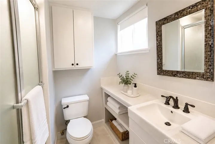Bright and functional bathroom featuring a modern vanity, abundant built-in storage, contemporary fixtures, and a large window that fills the space with natural light.