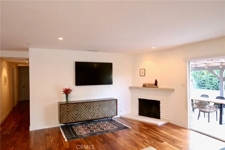 Gather in the inviting living room featuring a charming corner fireplace, spacious media wall, and sliding glass doors that create a seamless connection to the covered patio and beautifully landscaped backyard.