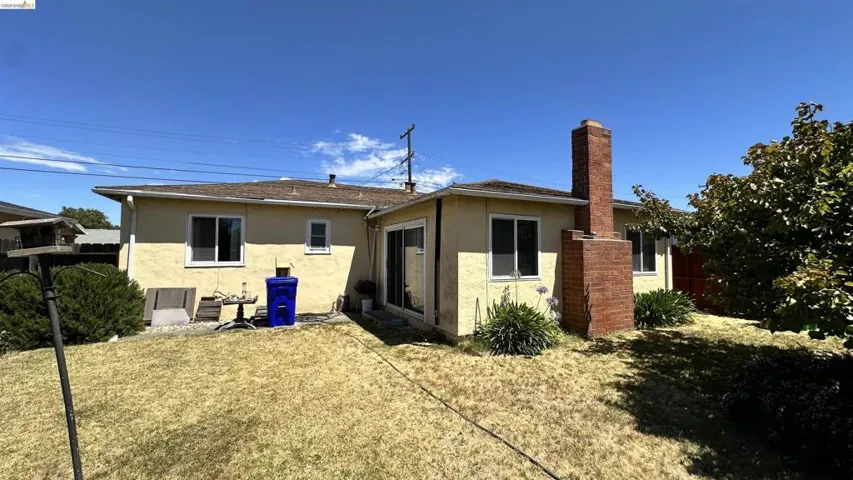 Rear exterior featuring a brick chimney, a sliding glass door, and multiple windows