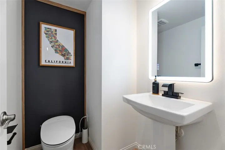 The stylish main-level powder room features a new Toto bidet, upgraded vanity with matte black fixtures, designer LED lighted mirror, and contemporary finishes that continue the home's elevated aesthetic.