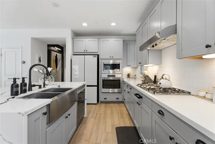 Quartz countertops surround the perimeter, while abundant cabinetry, stainless steel appliances, and expansive work surfaces provide exceptional functionality for everyday living.
