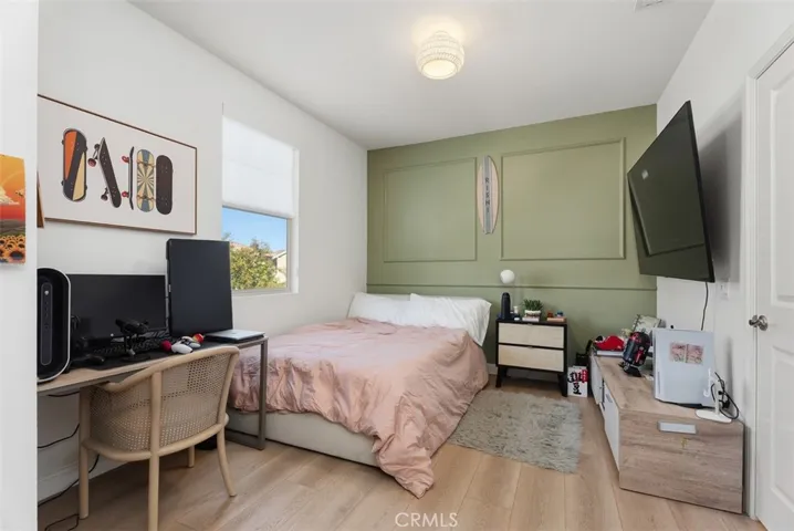 Spacious secondary bedroom with a custom designer accent wall, room for a desk or sitting area, and a walk-in closet featuring custom organization.