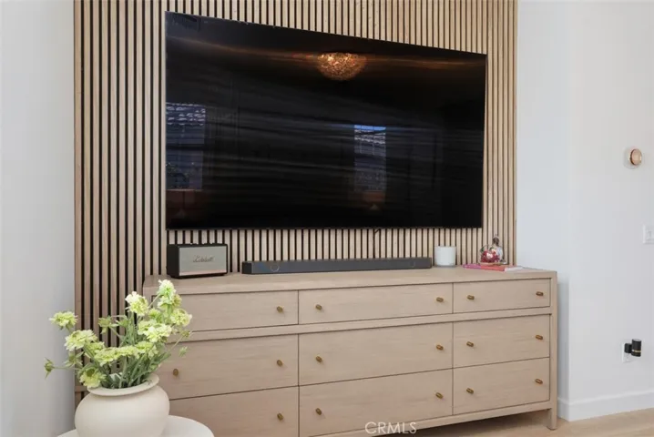 A custom wood slat accent wall creates a stunning focal point while providing the perfect backdrop for a wall-mounted television and built-in storage.