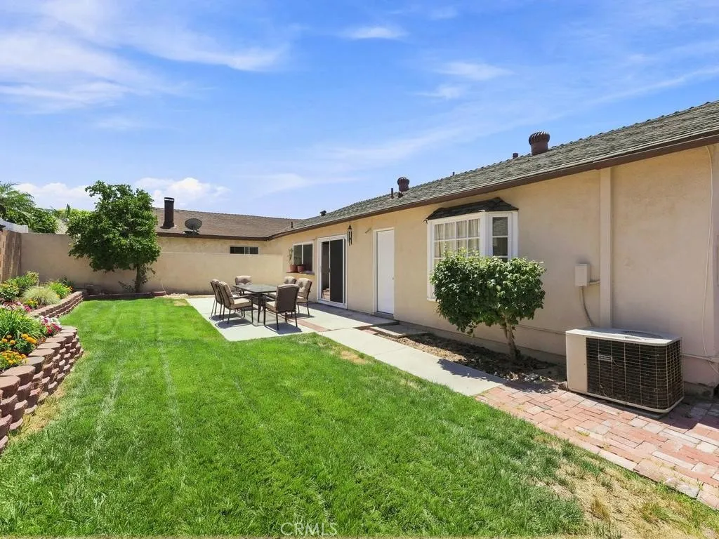 Nice size back yard with Virtually staged grass, planter bed with plants & furniture.