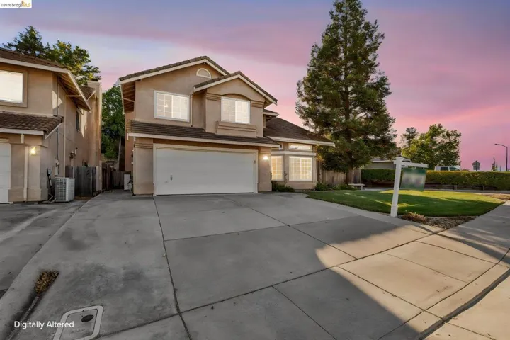 Two-story stucco residence featuring a two-car garage, bay window, and gabled roofline