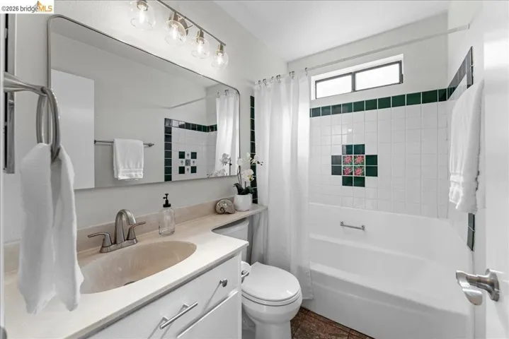 Bathroom featuring a built-in vanity with an undermount sink, brushed nickel faucet, and a large frameless mirror