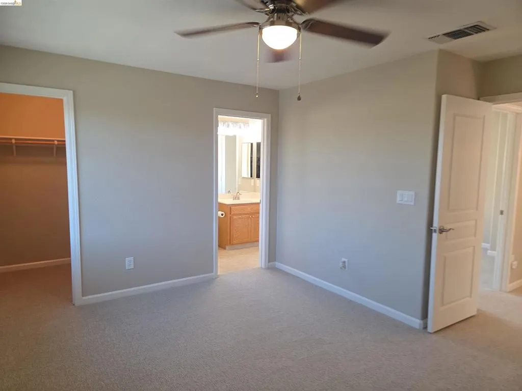 Carpeted room with a ceiling fan light fixture