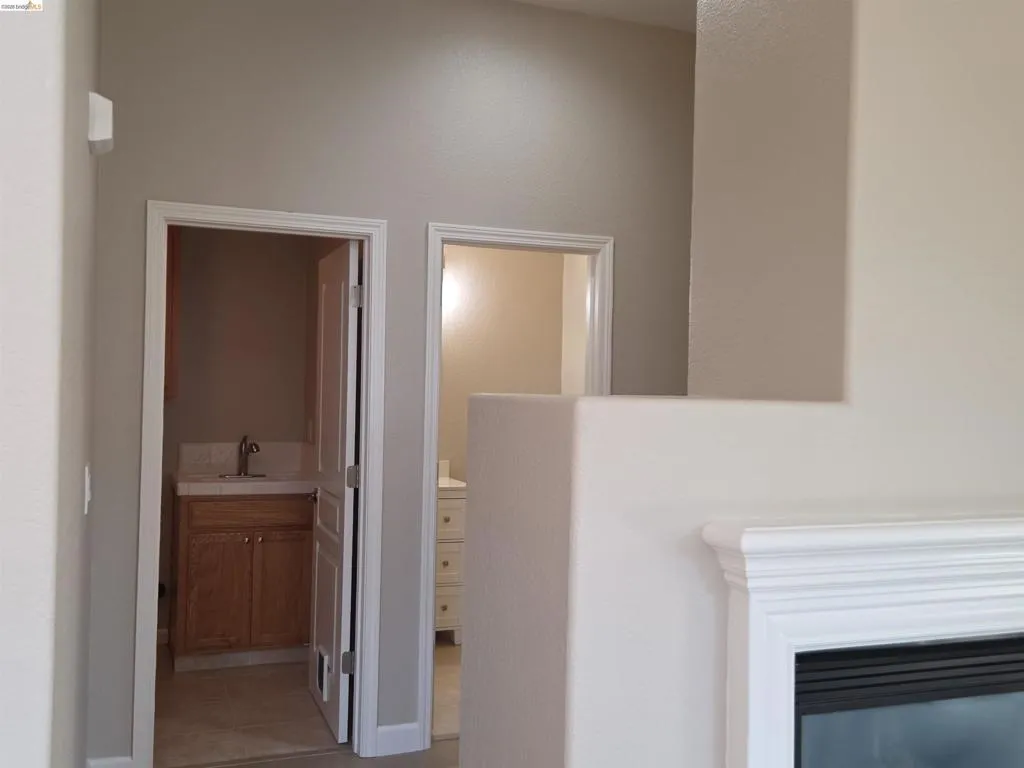 Integrated fireplace with a white mantel, two separate entries to rooms, light neutral wall paint, and white trim work