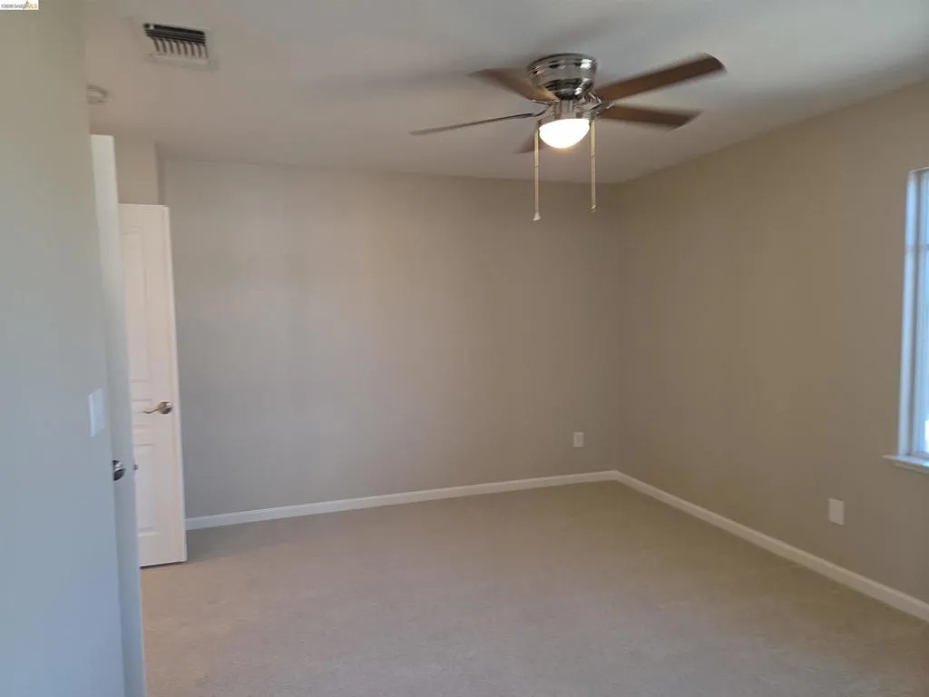 Carpeted room featuring neutral wall paint, a ceiling fan with integrated lighting, white baseboards, and a single window