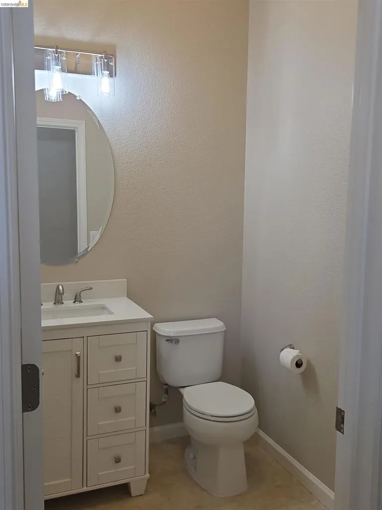 Compact bathroom featuring a white vanity with paneled drawer fronts, a white sink, and a chrome faucet