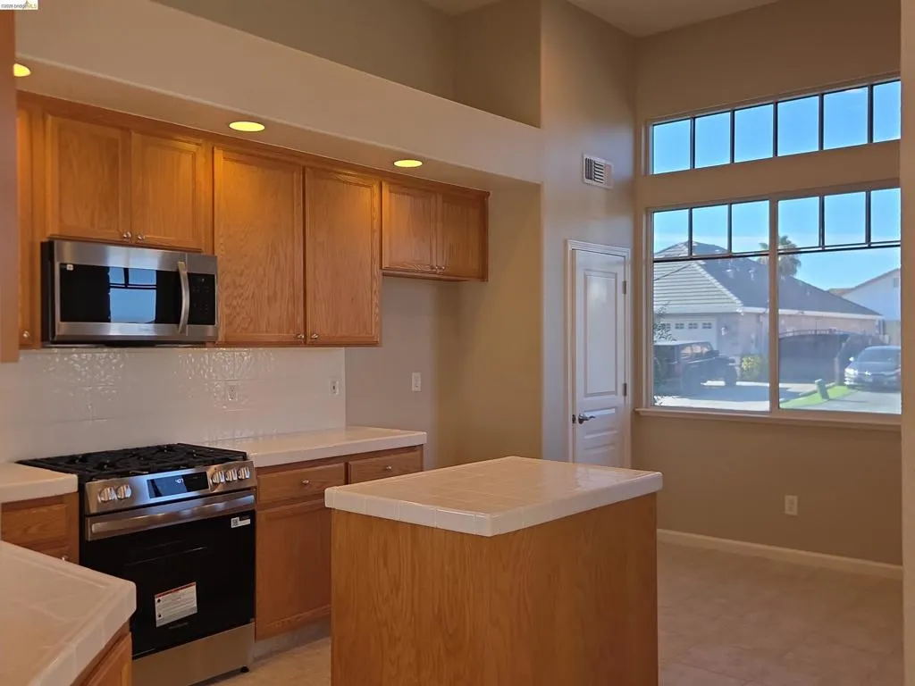 Kitchen featuring light wood cabinetry, a stainless steel microwave, and a gas range