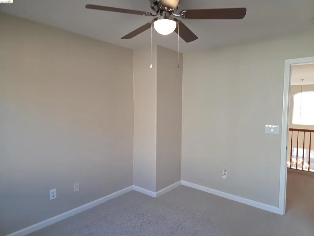 Carpeted room with neutral wall tones and white baseboards