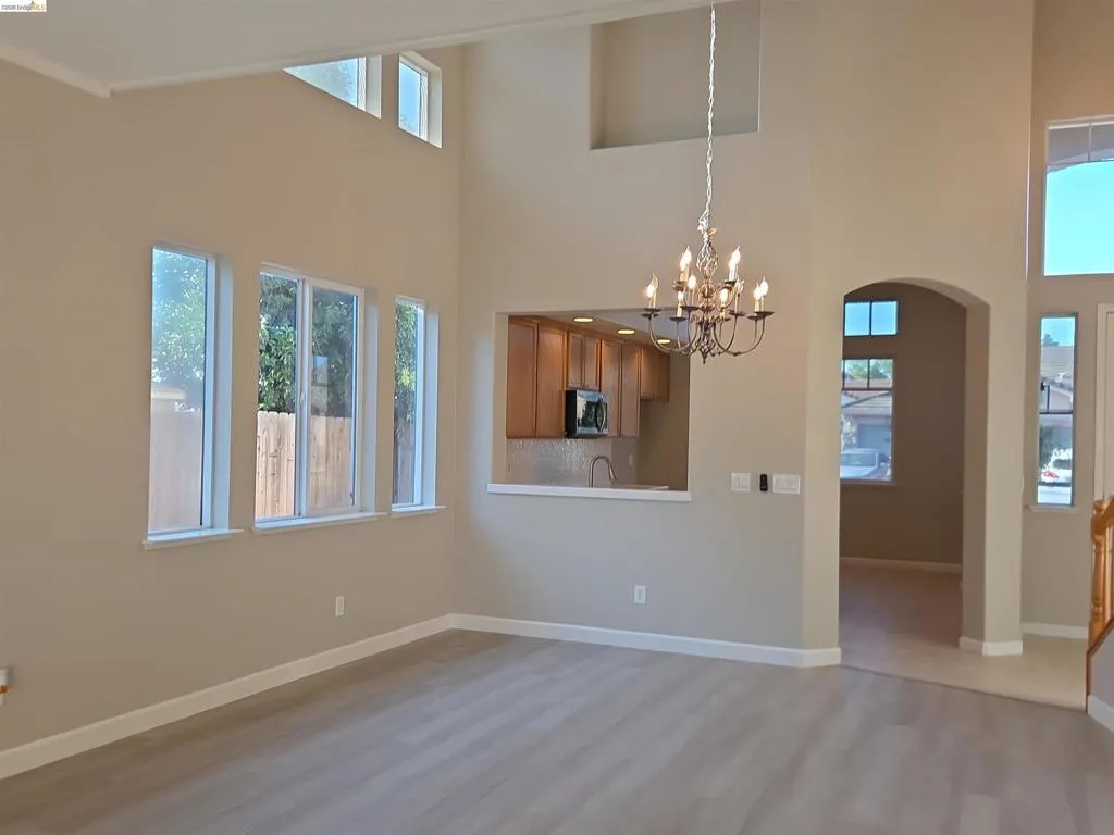 Open concept living space featuring high ceilings, light wood-finish flooring, and multiple windows