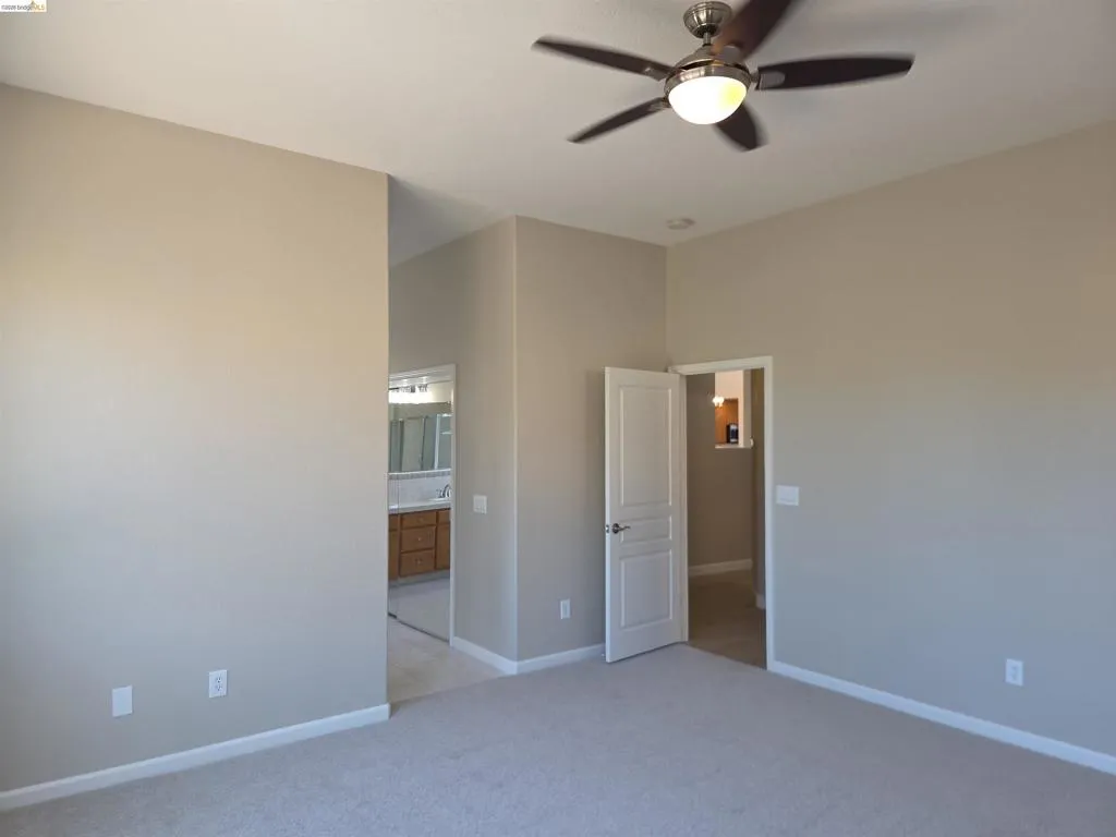 Carpeted interior space featuring a ceiling fan with light fixture